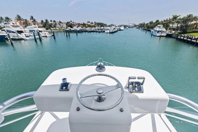 Slide: The Image of 2016 Hatteras Express Sportfish helm overlooking marina with yachts and palm trees. - 39