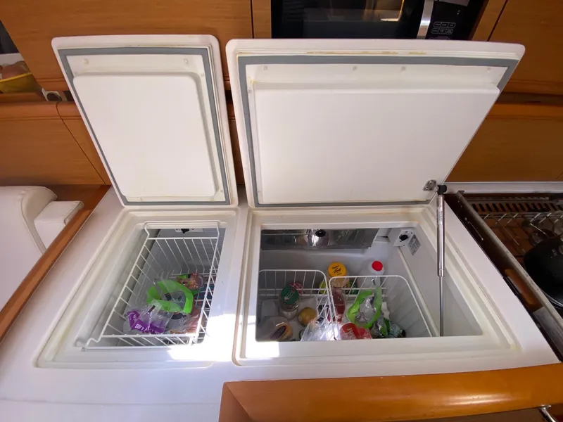 Slide: The Image of Interior view of Jeanneau Sun Odyssey 479's dual-compartment refrigerator, showcasing organized food storage. - 17