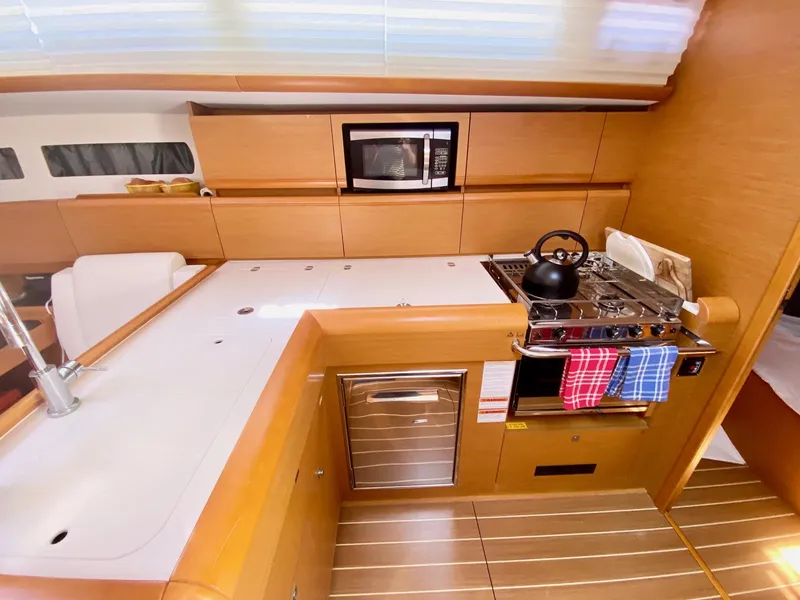 Slide: The Image of Modern kitchen in 2016 Jeanneau Sun Odyssey 479 yacht with stove, microwave, and sleek cabinetry. - 19