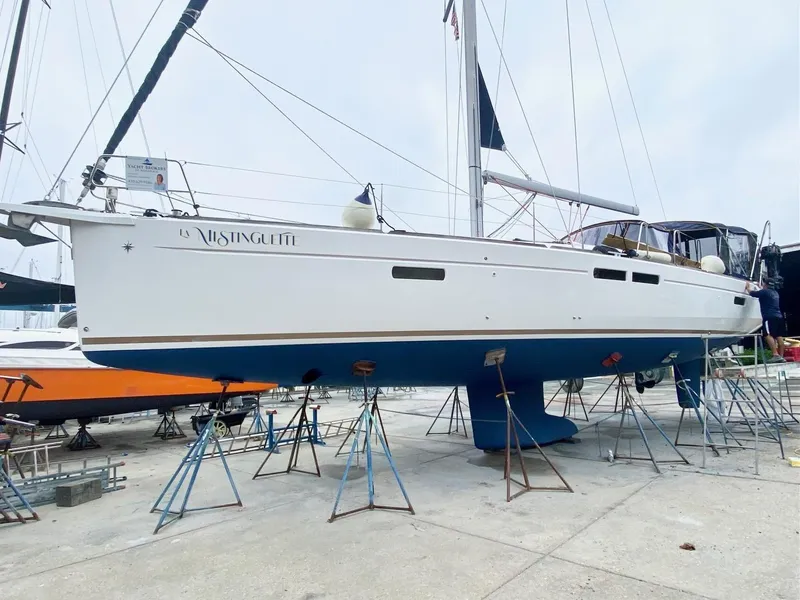 Slide: The Image of 2016 Jeanneau Sun Odyssey 479 sailboat on stands, white hull, blue bottom, marina background. - 47