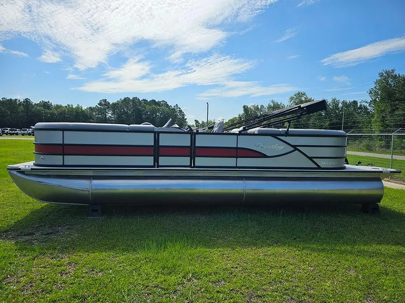Slide: The Image of 2025 Bentley Pontoons Legacy 243 Navigator on grass, showcasing sleek design and vibrant red accents. - 6