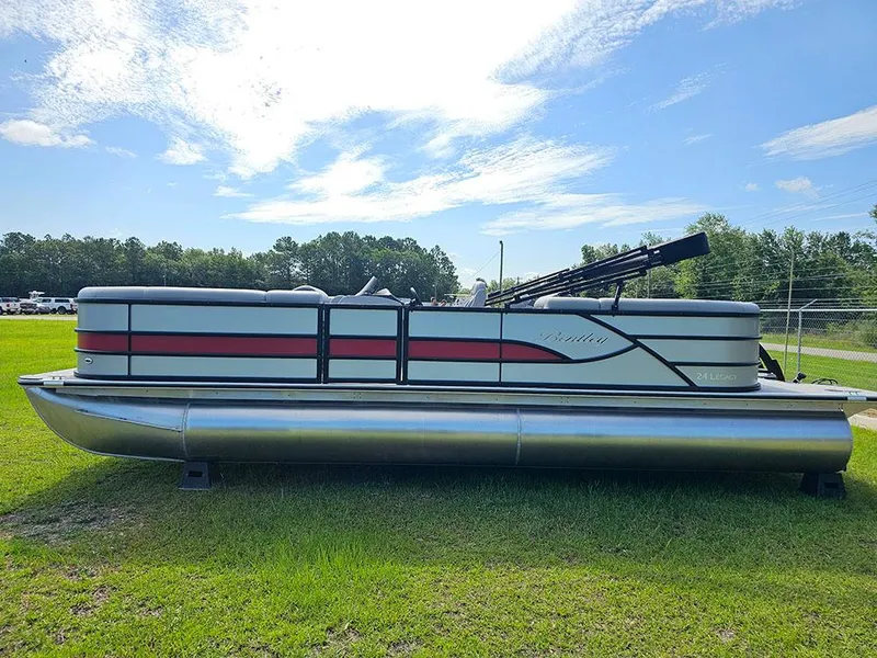Slide: The Image of 2025 Bentley Pontoons Legacy 243 Navigator on grass, showcasing sleek design and vibrant red accents. - 7