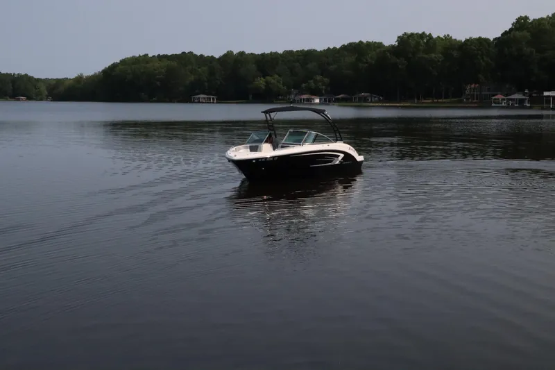 Slide: The Image of Chaparral 23 SSi 2020 boat cruising on a calm lake with forested shoreline. - 2