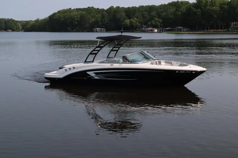 Slide: The Image of 2020 Chaparral 23 SSi boat cruising on a calm lake with forested shoreline. - 3