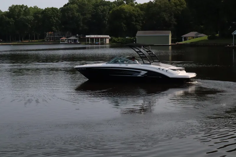 Slide: The Image of 2020 Chaparral 23 SSi boat cruising on a calm lake with wooded shoreline. - 6