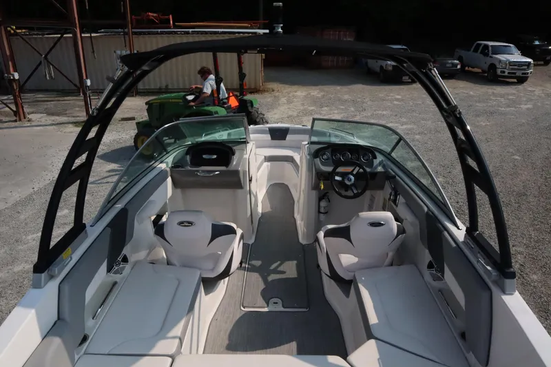 Slide: The Image of 2020 Chaparral 23 SSi boat interior with seating and steering wheel, parked on gravel. - 7