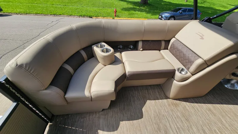 Slide: The Image of 2021 Bennington L 22 Quad Bench with beige upholstery and cup holders on a sunny day. - 16