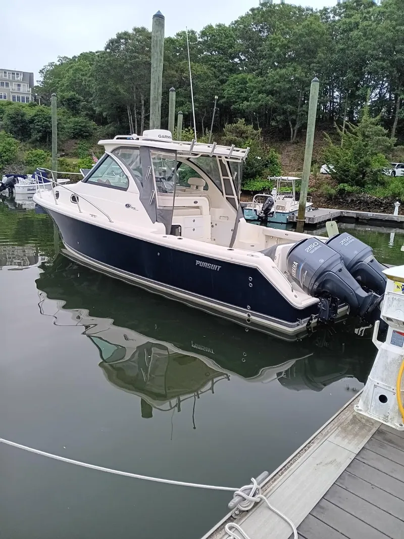 The Image of 2009 Pursuit 310 OS boat docked in a marina with twin outboard engines. - 1