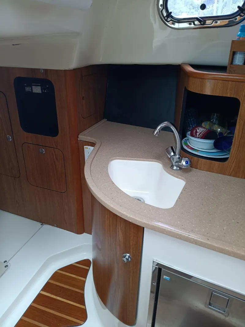 Slide: The Image of 2009 Pursuit 310 OS boat interior with kitchenette, sink, and wooden cabinetry. - 11