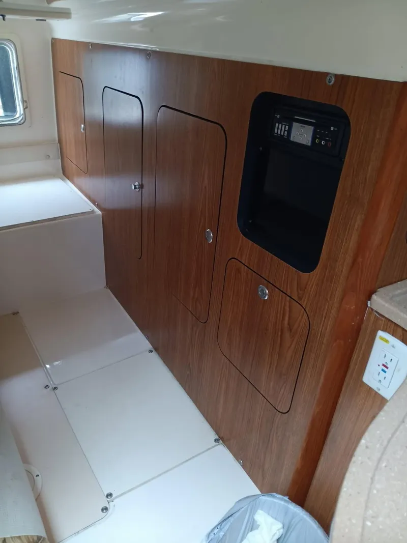 Slide: The Image of Interior of a 2009 Pursuit 310 OS boat, featuring wooden cabinetry and control panel. - 12