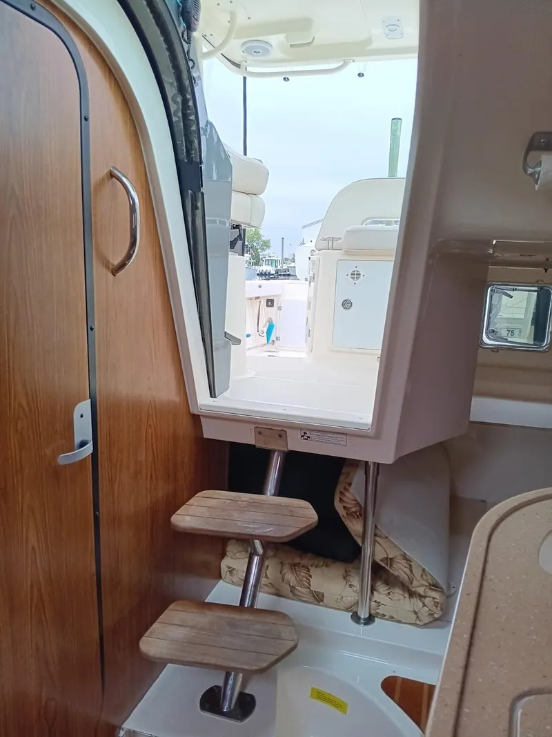Slide: The Image of Interior view of 2009 Pursuit 310 OS boat, featuring wooden steps and cabin entrance. - 15