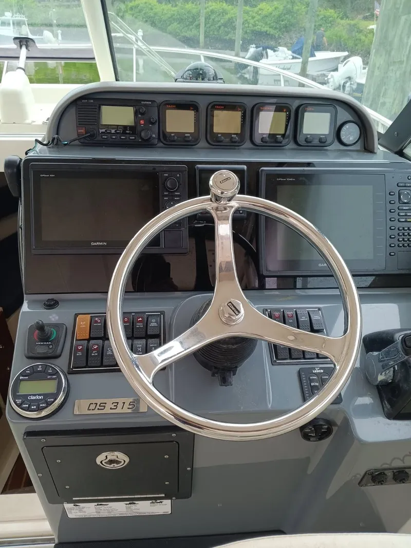 Slide: The Image of 2009 Pursuit 310 OS boat helm with steering wheel and navigation controls. - 9
