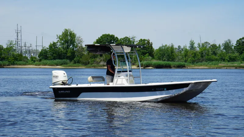 The Image of 2020 Sundance B22CR boat cruising on a calm river with lush green shoreline. - 1