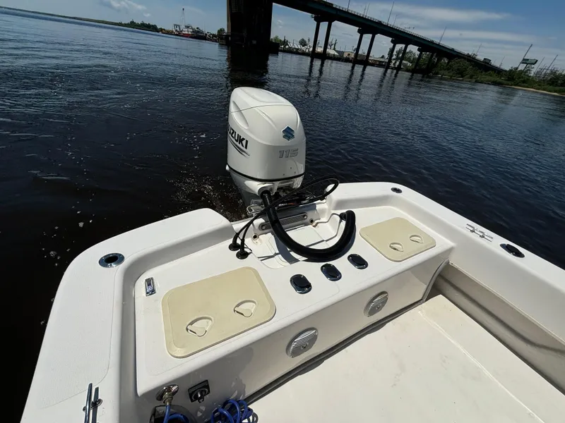 Slide: The Image of 2020 Sundance B22CR boat with Suzuki outboard motor on a calm river near a bridge. - 13