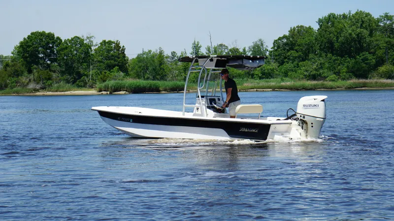 Slide: The Image of 2020 Sundance B22CR boat cruising on a calm river with lush green trees. - 3