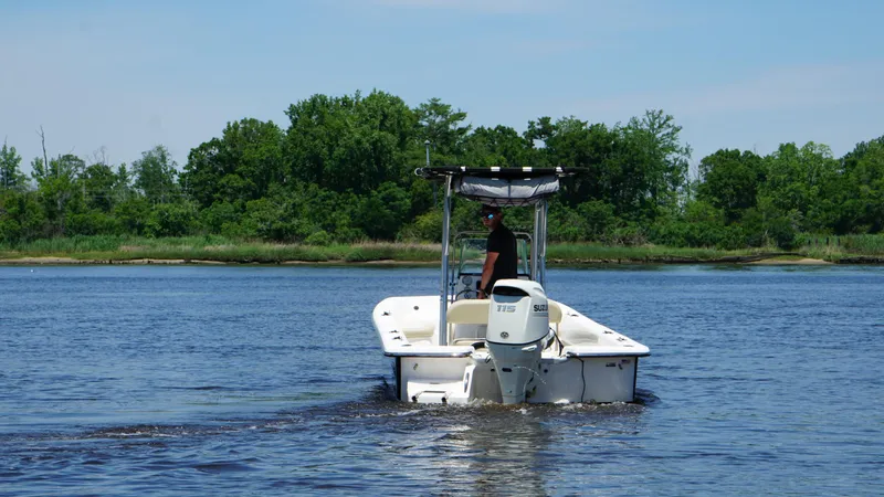 Slide: The Image of A 2020 Sundance B22CR boat cruising on a calm lake with lush green trees. - 5