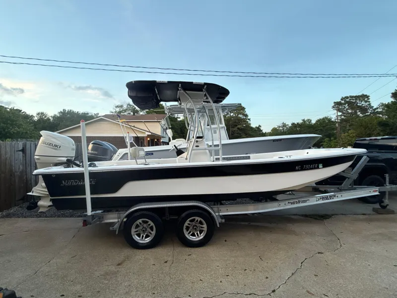 Slide: The Image of 2020 Sundance B22CR boat on trailer with Suzuki outboard motor, parked outdoors. - 6