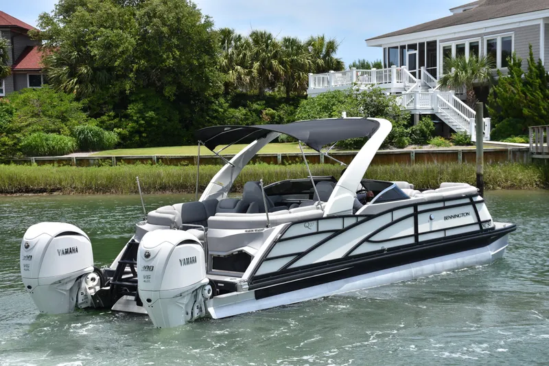 Slide: The Image of 2024 Bennington 27 QFB pontoon boat cruising near waterfront homes. - 15