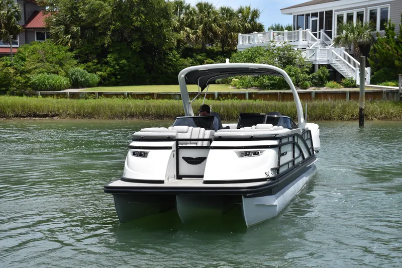 Slide: The Image of 2024 Bennington 27 QFB pontoon boat cruising on a scenic waterway. - 25