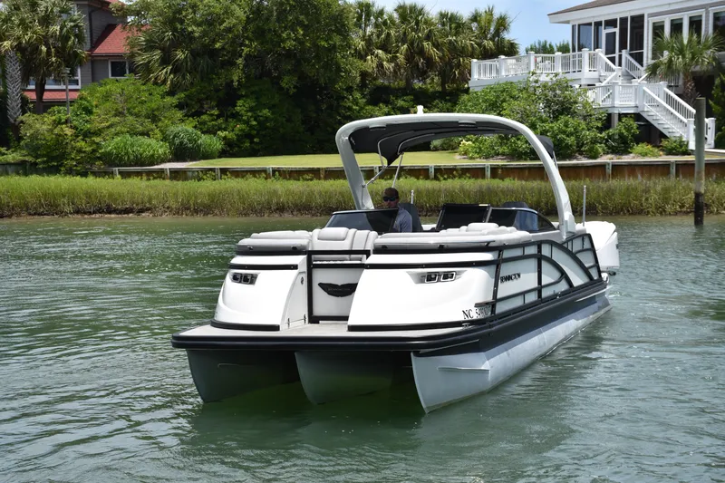 Slide: The Image of 2024 Bennington 27 QFB pontoon boat cruising on a scenic waterway. - 26