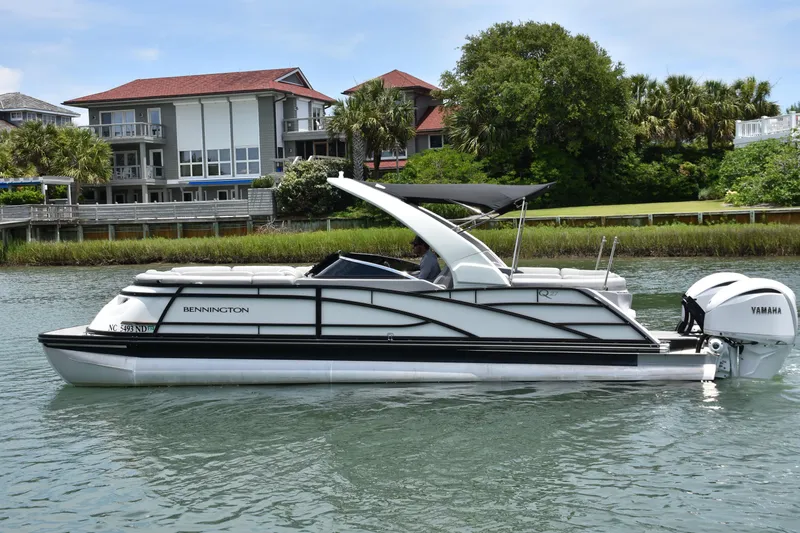 Slide: The Image of 2024 Bennington 27 QFB pontoon boat on water, with Yamaha engine, near waterfront homes. - 31