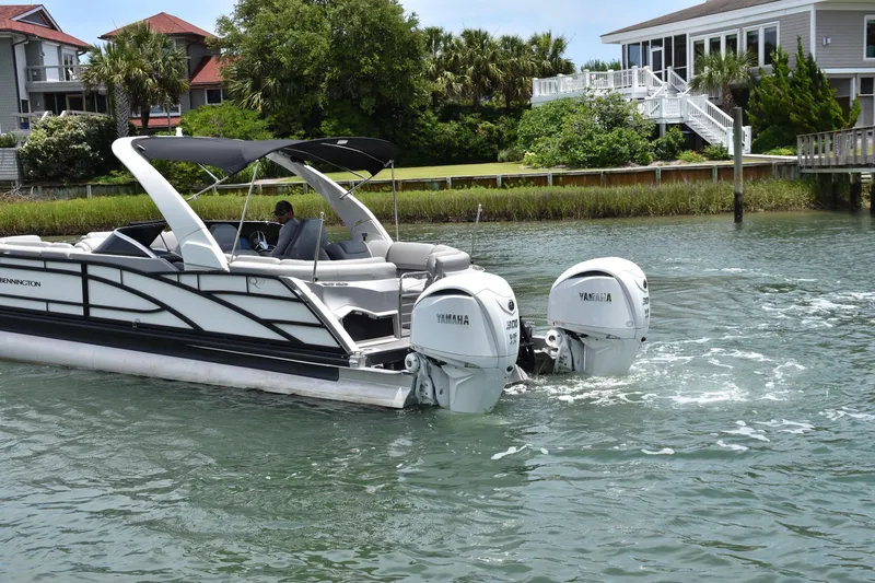 Slide: The Image of 2024 Bennington 27 QFB pontoon boat with dual Yamaha engines on a scenic waterway. - 33