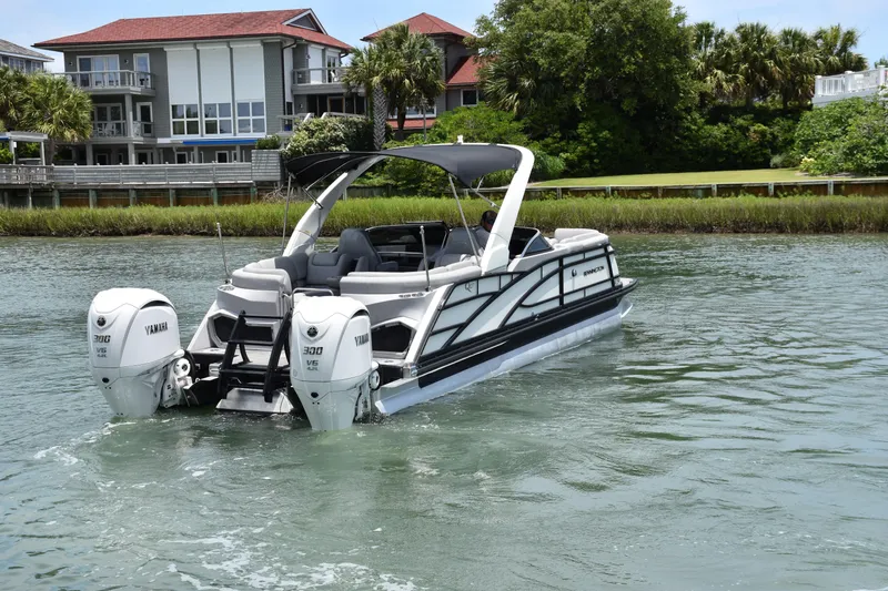 Slide: The Image of 2024 Bennington 27 QFB pontoon boat with dual Yamaha engines on a scenic waterway. - 36