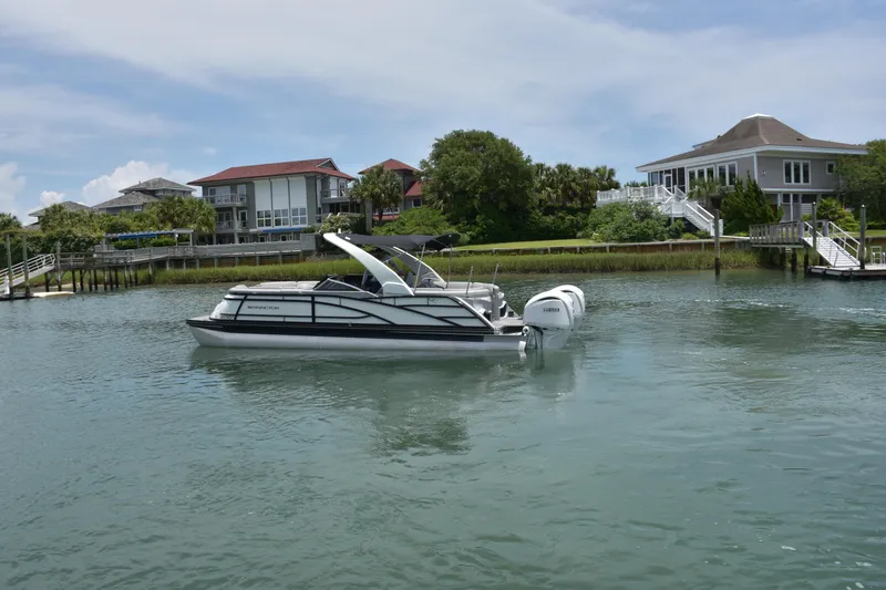 Slide: The Image of 2024 Bennington 27 QFB pontoon boat on calm water near waterfront homes. - 4