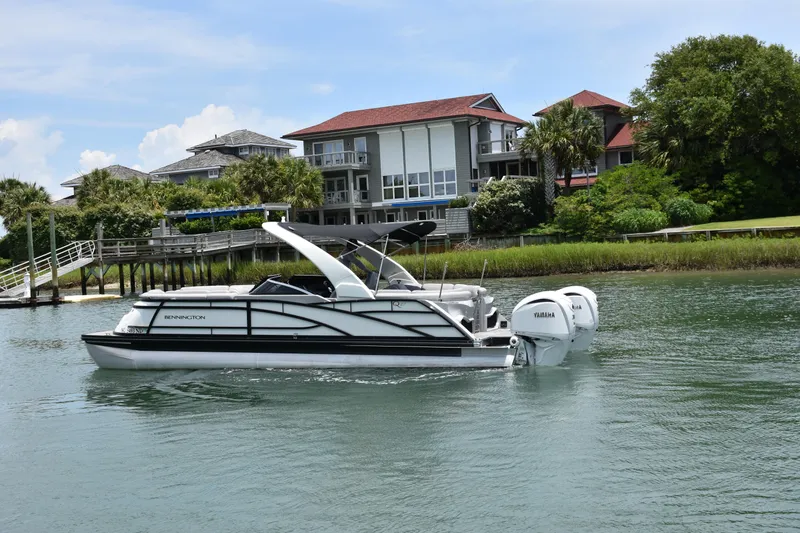 Slide: The Image of 2024 Bennington 27 QFB boat cruising near waterfront homes. - 6