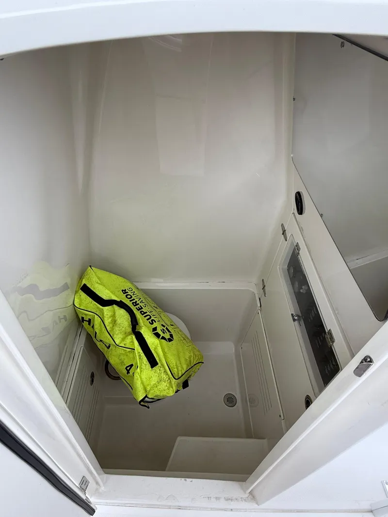 Slide: The Image of Storage compartment in a 2012 Jupiter 26 boat with a yellow bag inside. - 13