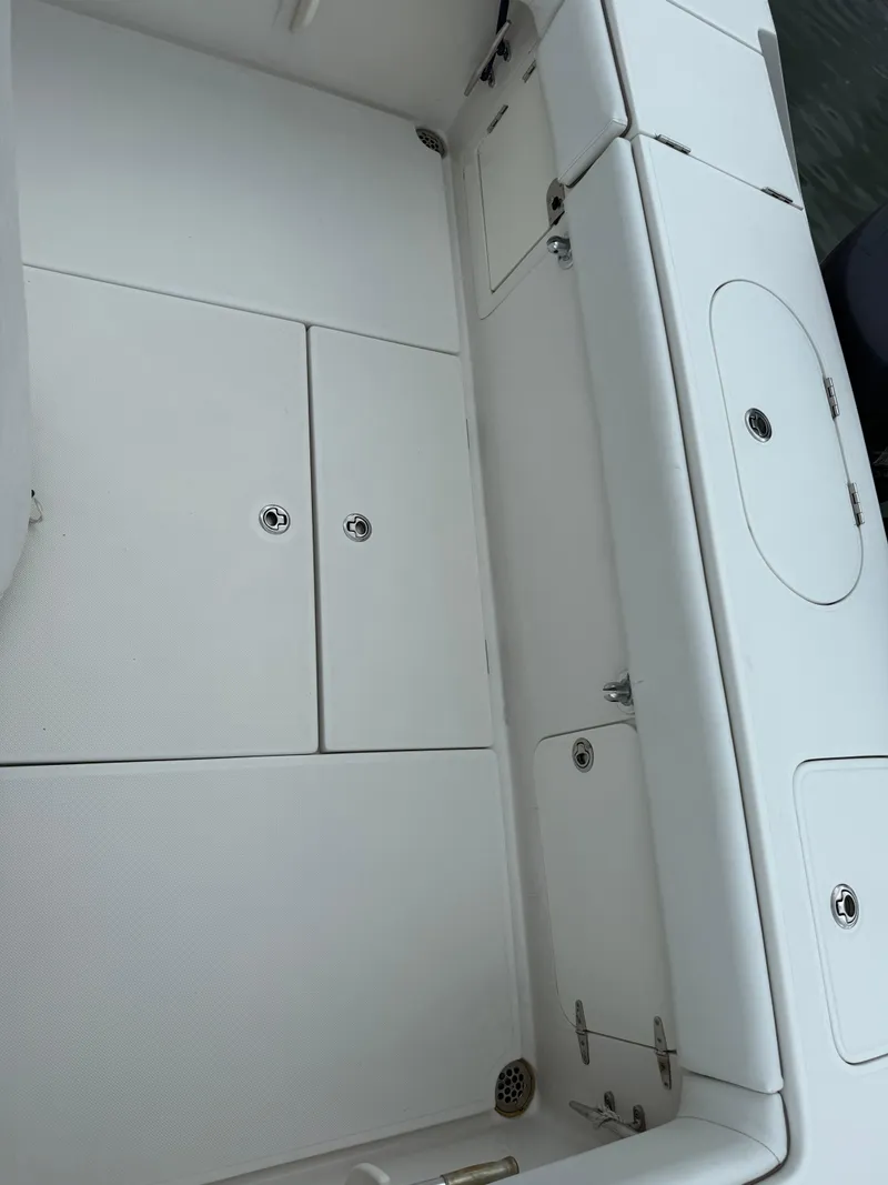 Slide: The Image of White interior of a 2012 Jupiter 26 boat, featuring storage compartments. - 14