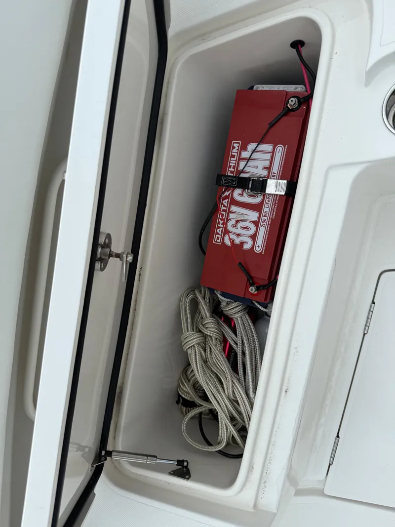 Slide: The Image of Storage compartment in a 2012 Jupiter 26 boat with battery and coiled rope. - 16