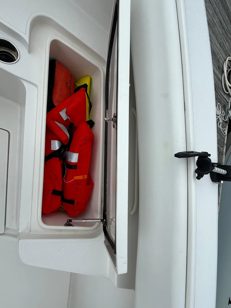 Slide: The Image of Open storage compartment on 2012 Jupiter 26 boat with life jackets inside. - 17