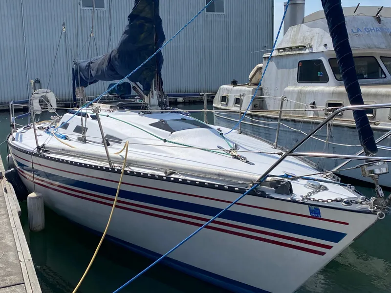 The Image of 1979 Santana 35 sailboat docked, featuring red and blue stripes on the hull. - 0