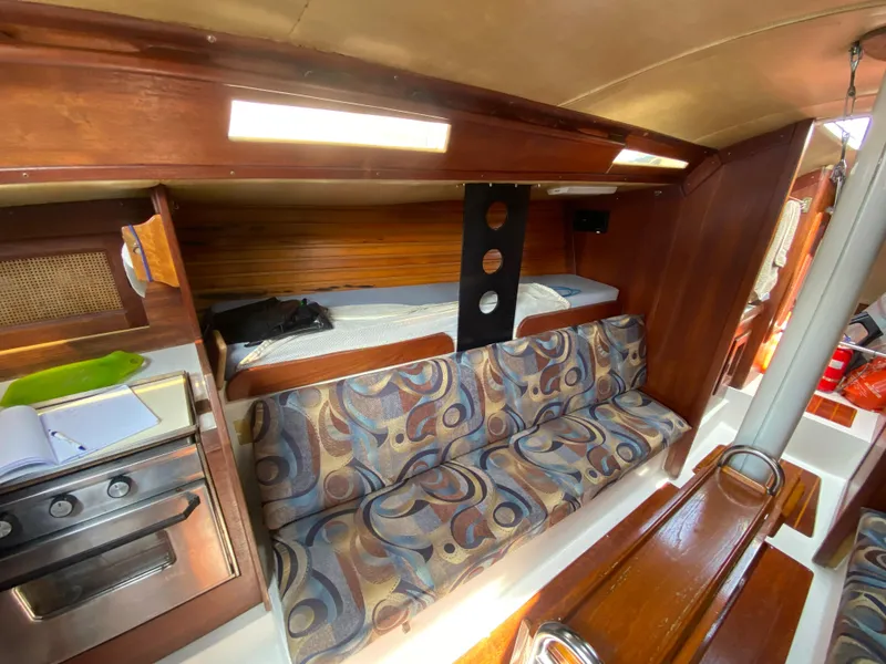 Slide: The Image of 1979 Santana 35 yacht interior with patterned seating and compact kitchen area. - 13