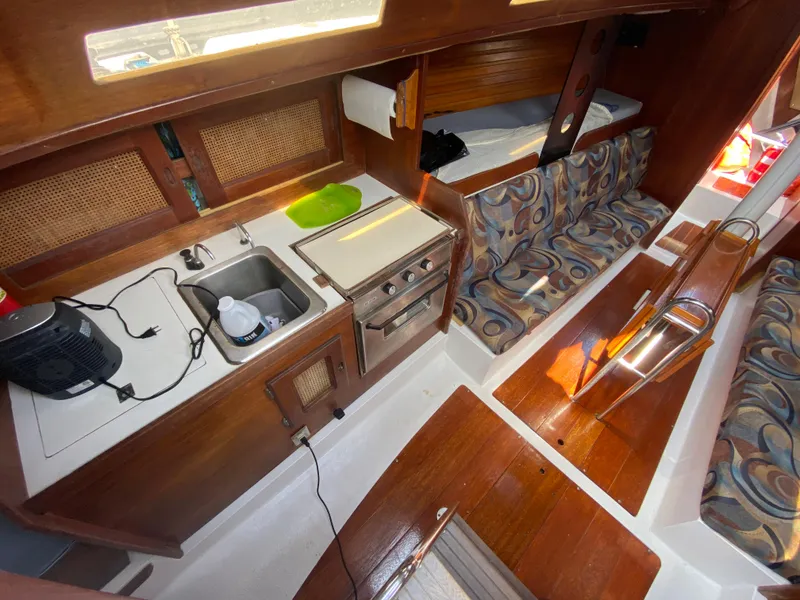 Slide: The Image of 1979 Santana 35 yacht interior with kitchen, sink, stove, and patterned seating. - 14