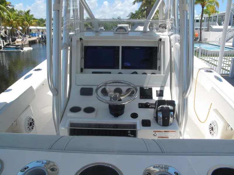 Slide: The Image of 2020 SeaVee 290B boat console with dual screens and steering wheel, docked near palm trees. - 15