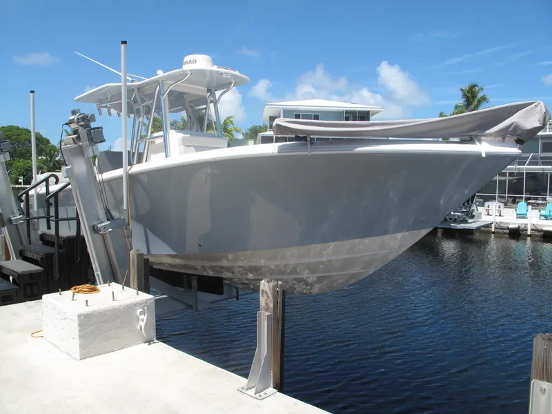Slide: The Image of 2020 SeaVee 290B boat on lift at marina, clear sky background. - 2