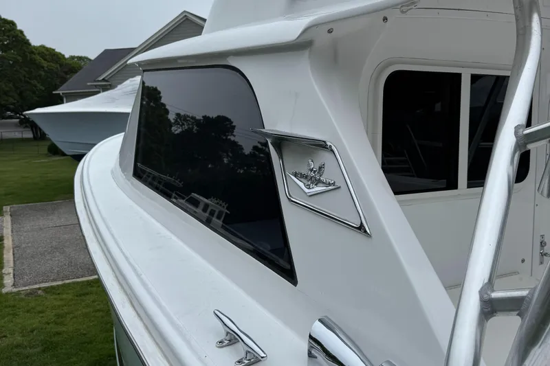 Slide: The Image of 1964 Bertram 31 Flybridge Cruiser, side view with logo, parked near a house. - 17