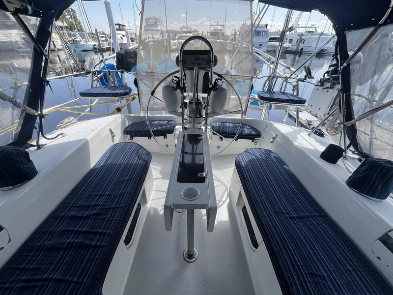 Slide: The Image of 1999 Catalina 42 MkII yacht cockpit with blue-striped seating, docked at marina. - 10