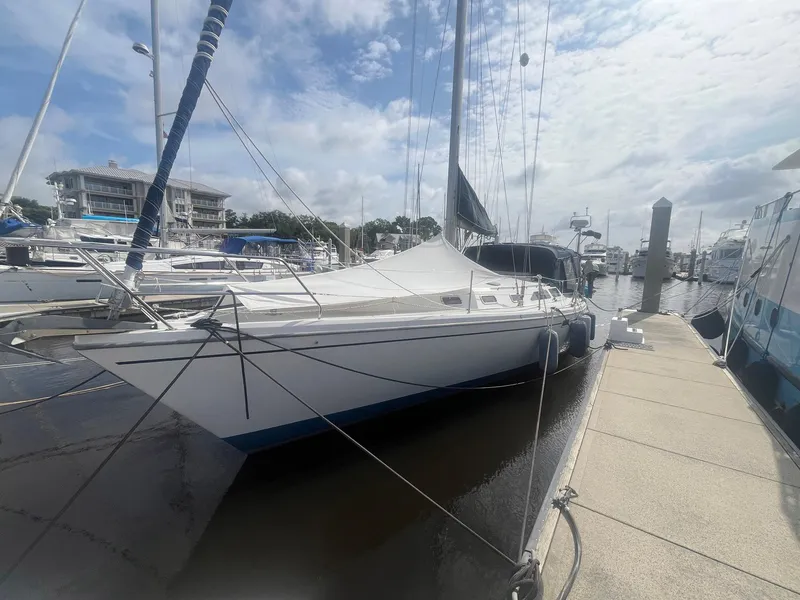 Slide: The Image of 1999 Catalina 42 MkII sailboat docked at a marina under a partly cloudy sky. - 5