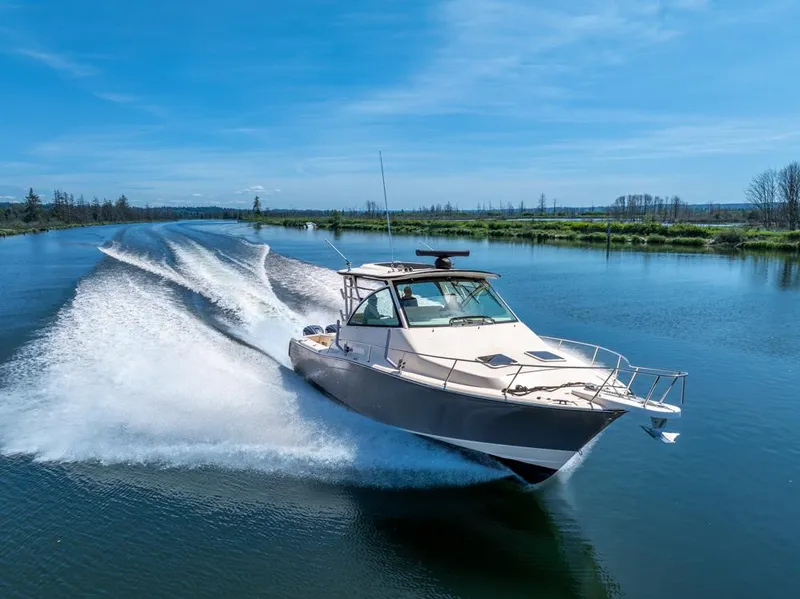 Slide: The Image of 2019 Grady-White Express boat cruising on a serene river under a clear blue sky. - 6