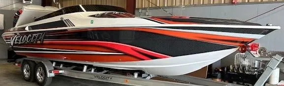 The Image of 2021 Velocity 290 SC speedboat with vibrant red and black design on a trailer. - 0
