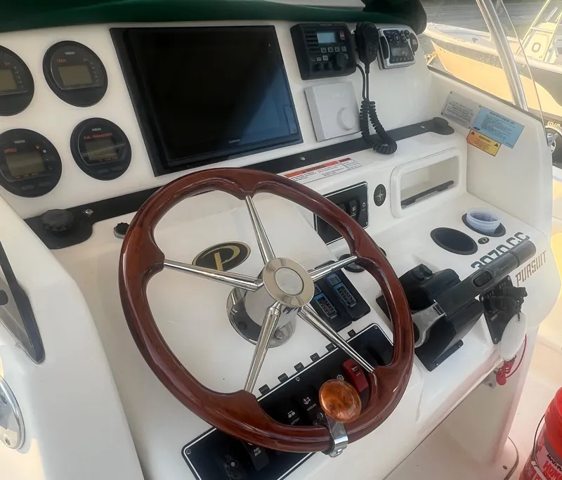 Slide: The Image of 2001 Pursuit 3070 Center Console boat dashboard with steering wheel and control panel. - 11