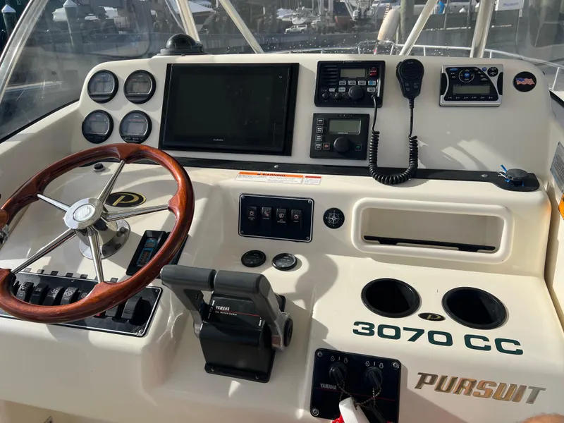 Slide: The Image of 2001 Pursuit 3070 Center Console boat dashboard with steering wheel and controls. - 12