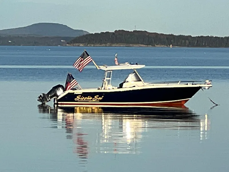 Slide: The Image of 2001 Pursuit 3070 Center Console boat on calm water with American flags. - 17