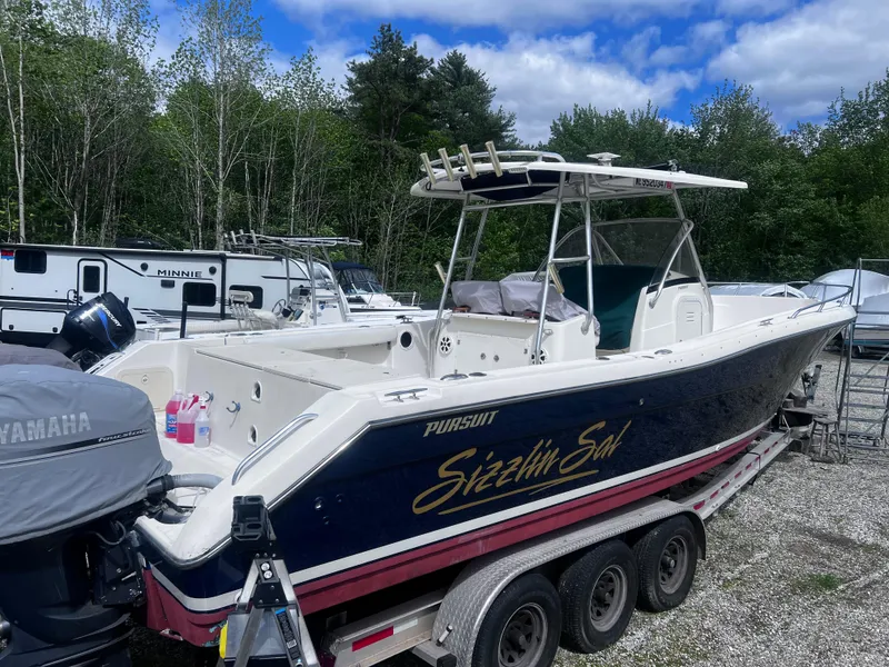 The Image of 2001 Pursuit 3070 Center Console boat on trailer, surrounded by trees and RVs. - 2