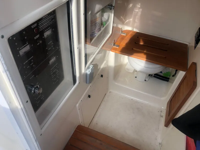 Slide: The Image of 2001 Pursuit 3070 Center Console boat interior with control panel and compact toilet area. - 20