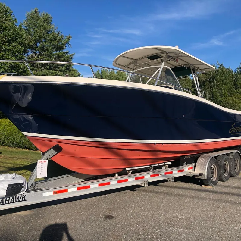 Slide: The Image of 2001 Pursuit 3070 Center Console boat on trailer, blue and red hull, sunny day. - 28