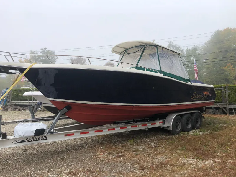 Slide: The Image of 2001 Pursuit 3070 Center Console boat on trailer, foggy background, American flag visible. - 30